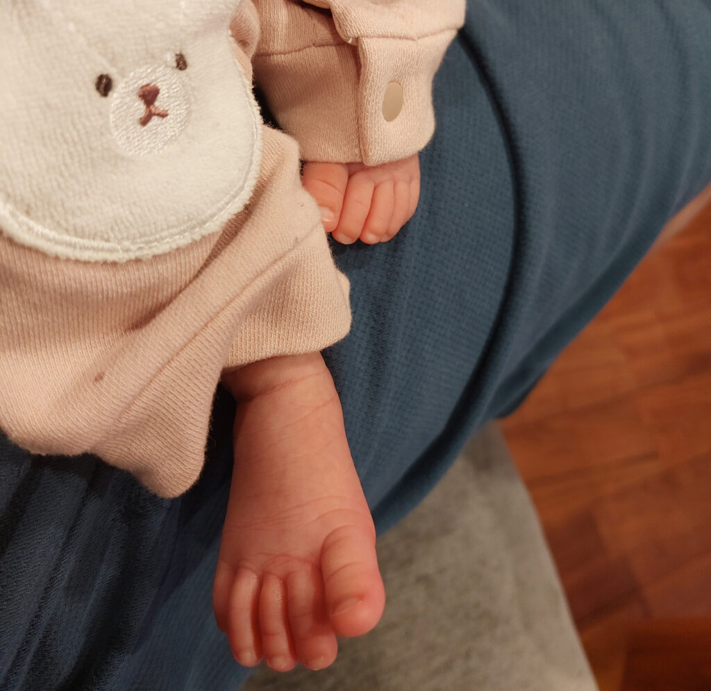 新米パパの膝の上にいる生まれたばかりの我が子の様子