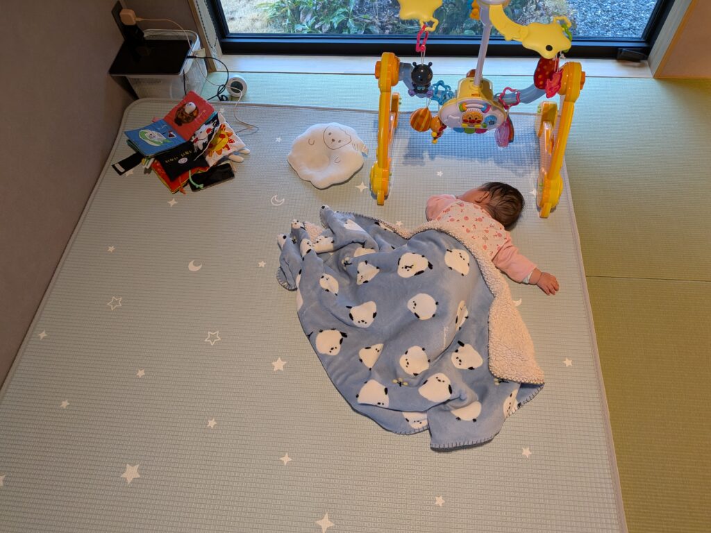 和室にプレイマットを敷いている様子。遊び疲れて赤ちゃんが寝ている